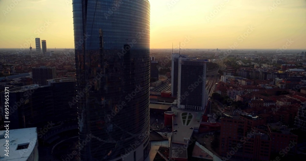 Obraz premium Towering glass skyscraper defining downtown skyline, with office towers, train tracks and roads