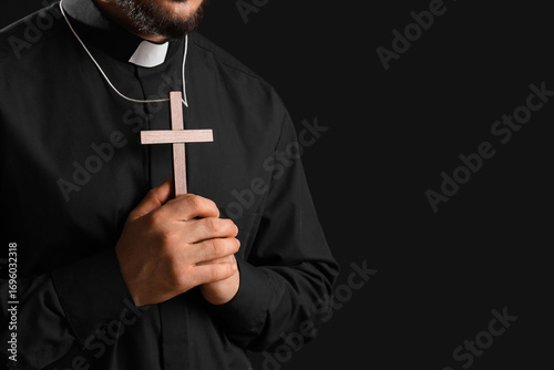 Fotografie Priest in black clerical shirt holding a wooden cross, religious faith and spiri