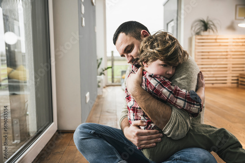 Father and son hugging each other on floor at home