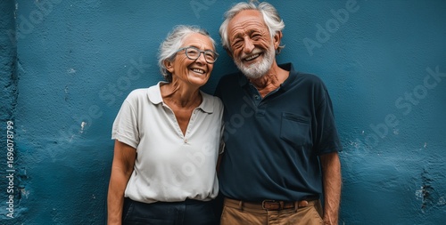 Elderly Couple Enjoying a Joyful Moment Against a Vibrant Blue Wall in a Sunn...
