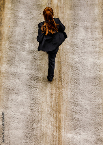 A woman in a black suit walks on a waterfall.