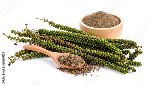 Fresh green peppercorns and ground pepper in a wooden bowl and scoop. Clusters of peppercorns are arranged next to a small bowl of ground spices, on a stark white background