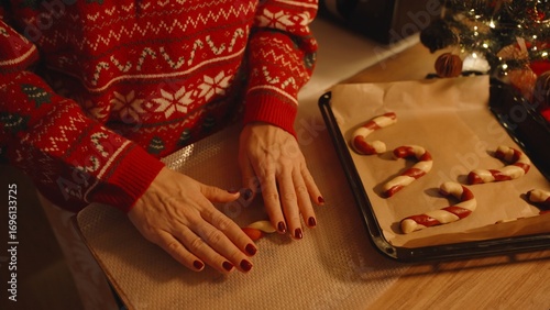 Woman in Festive Sweater Rolling Dough into Candy Cane Near Baking Tray with Already Shaped Cookies, Holiday Cookie Craft Concept