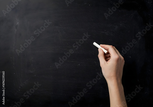 A hand holding chalk on a blackboard.