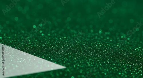 Close-up of a white triangular shape on a deep green glitter background.