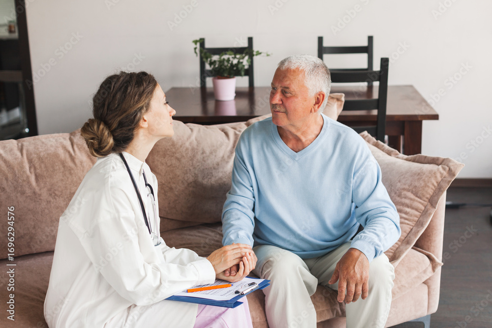 Obraz premium Female professional doctor showing medical test result explaining prescription using clipboard visiting senior elderly old man patient at home sitting on sofa