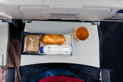 Overhead view of simple mealbox with light snack, apple juice and water served in short haul flight in Malaysia