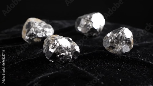 Shiny Silver Minerals on Black Velvet - Four shiny silver mineral samples are artfully arranged on a piece of black velvet fabric. The dark background enhances the metallic gleam of the stones.