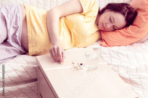 pregnant woman reaches out its arm for a pill