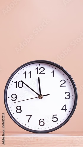 4K footage vertical video Time-lapse, Wall clock with black frame and bold black numbers on wooden shelf against soft beige background showing the time 11:41, Concept of time punctuality.