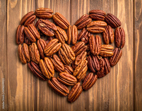 Pile of love shaped pecans on a wooden background.