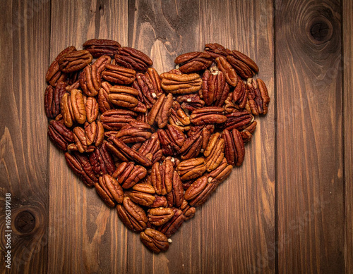 Pile of love shaped pecans on a wooden background.