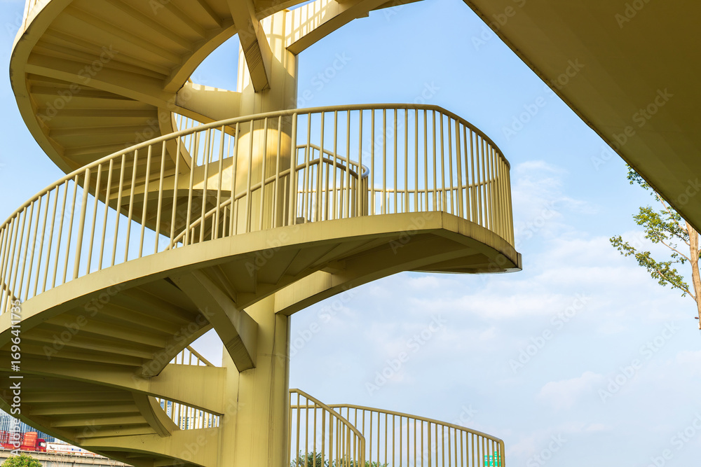 Fototapeta premium A spiral staircase against the backdrop of blue sky and white clouds