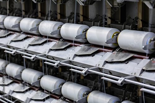 The machine is producing white polyester yarn bobbins.