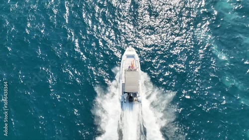Aerial drone tracking cinematic video of inflatable rib speed boat cruising in high speed in mediterranean deep blue sea bay