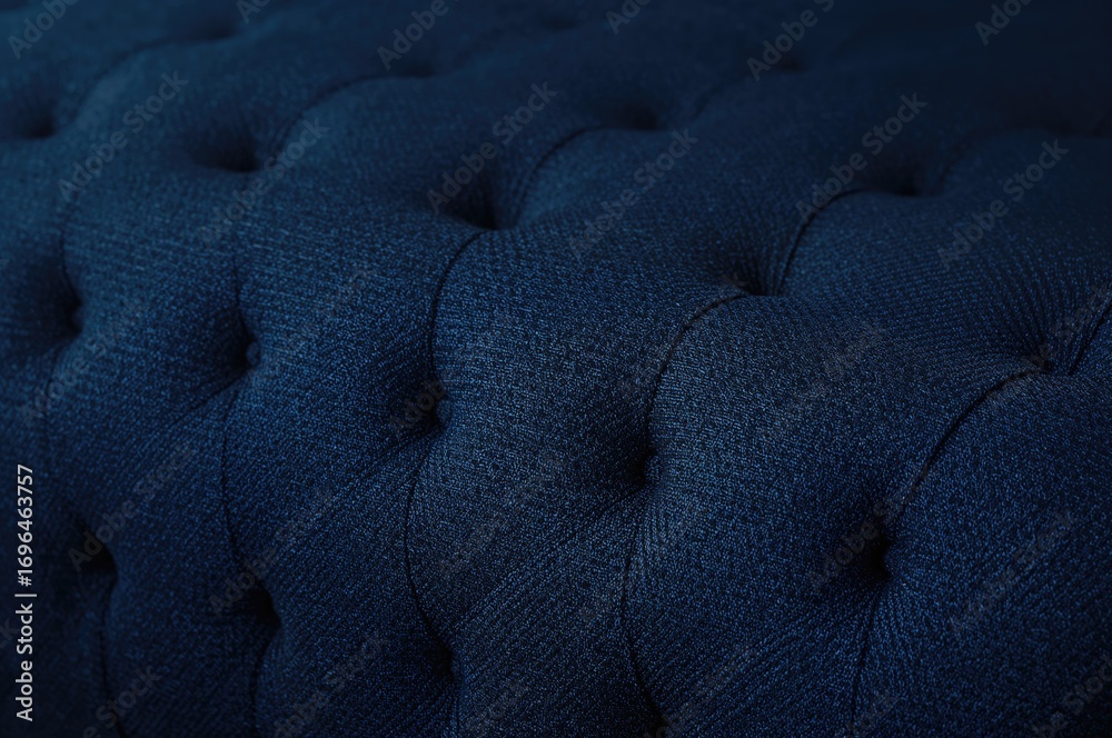Obraz premium Close-up of tufted fabric furniture with diamond button pattern on dark blue textile background in vintage style