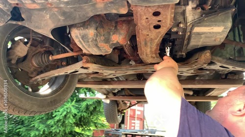 A car mechanic repairs a car using a wrench.