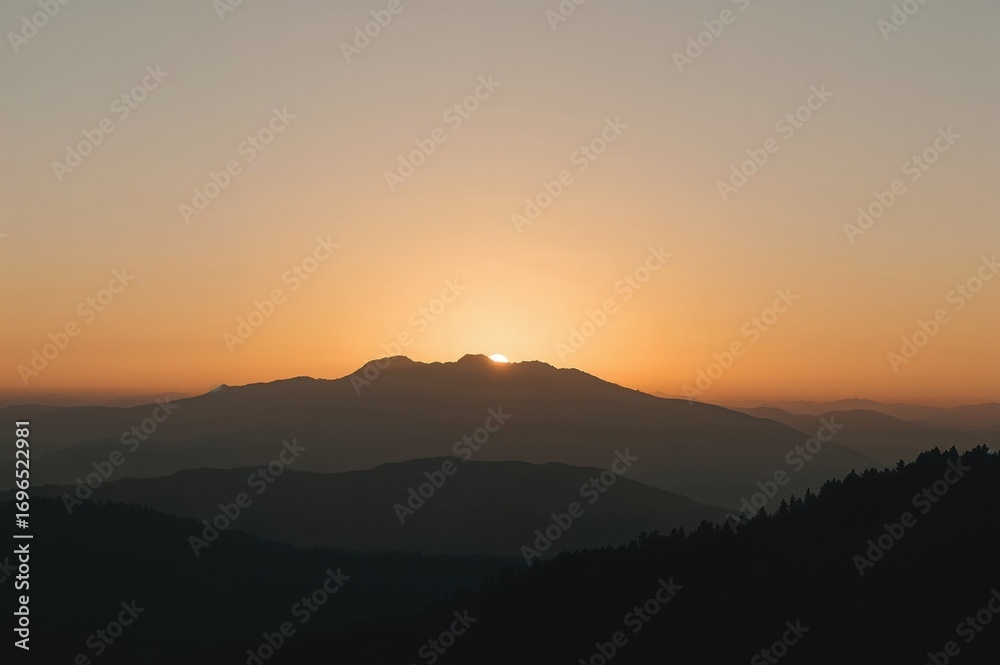Fototapeta premium Sunrise behind a foggy mountain outline