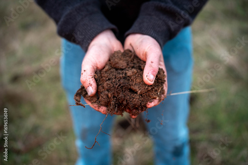 modern young farmer collecting soil samples in a test tube in a field. Agronomist checking soil carbon and plant health on a farm