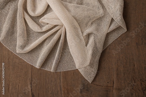 Delicate mesh lace fabric spread over a rustic wooden surface, showcasing intricate texture and elegant draping