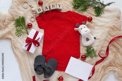 Christmas composition for baby or pregnancy announcement, red baby bodysuit mockup for text presentation, card for ultrasound photo, flat lay with baby toys, gift and Christmas decorations.