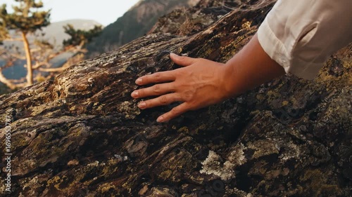 woman hand touching stone rock. hand close up. texture of ancient rocks mountains nature. traveler girl climbing rocks at sunset summer. panoramic view city capital Andorra la Vella. moss-grown stone