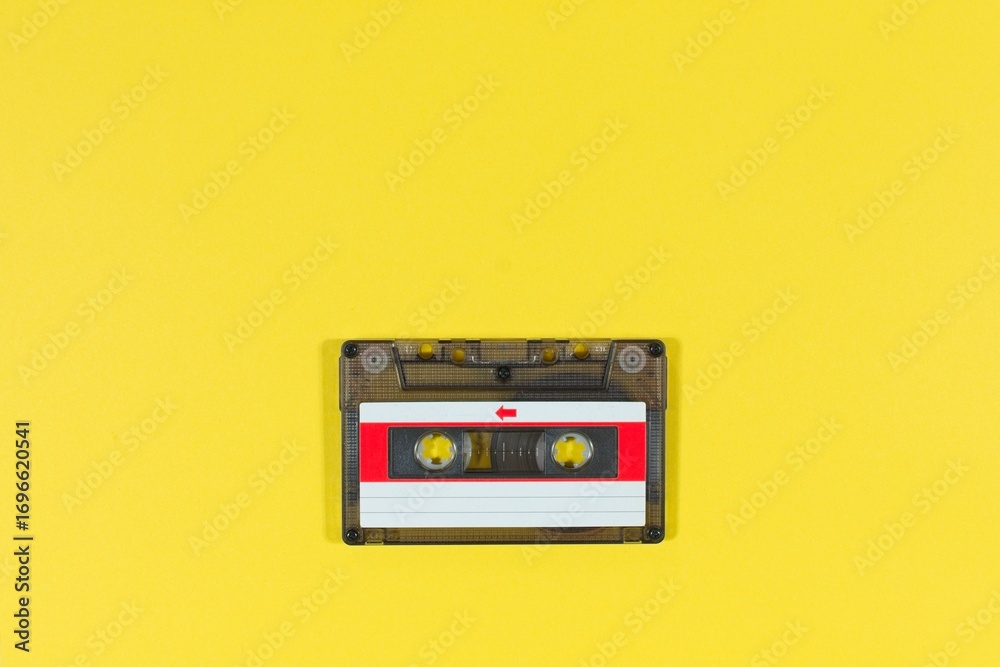 Fototapeta premium Overhead view of a vintage audio music cassette tape on a yellow background with copy space.