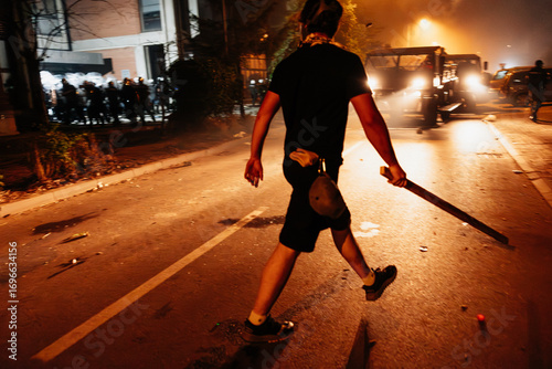 Demonstrators engage in protests on urban streets at night with tensions rising and vehicles present in the background