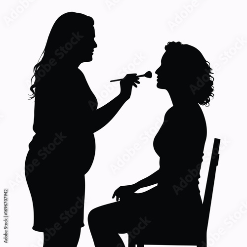 Silhouette of makeup artist applying makeup to seated client