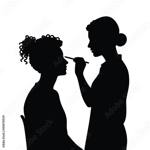Silhouette of makeup artist applying makeup to woman with curly hair Keywords: silhouette