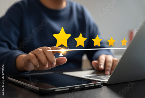 User giving five-star rating on digital interface using laptop and tablet, representing customer satisfaction, online review system, and quality feedback experience in digital platforms.