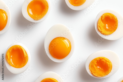 Sliced hard-boiled eggs arranged in a scattered pattern. Protein-rich egg halves isolated on white background, showcasing vibrant yolks and clean simplicity.