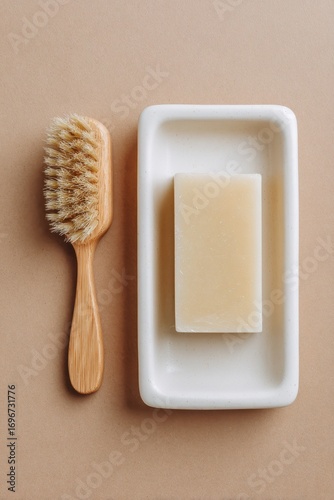 Wooden brush and soap bar in a white soap dish.