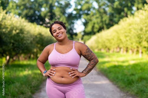 Smiling natural plus size woman in workout clothing outdoors