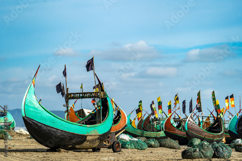 Colorful fishing boats on a sandy beach under a blue sky at Teknaf Sea Beach. Colorful Wooden Fishing Boat On a Cox's Bazar Sea Beach, Bangladesh With Blue Sky Background. 