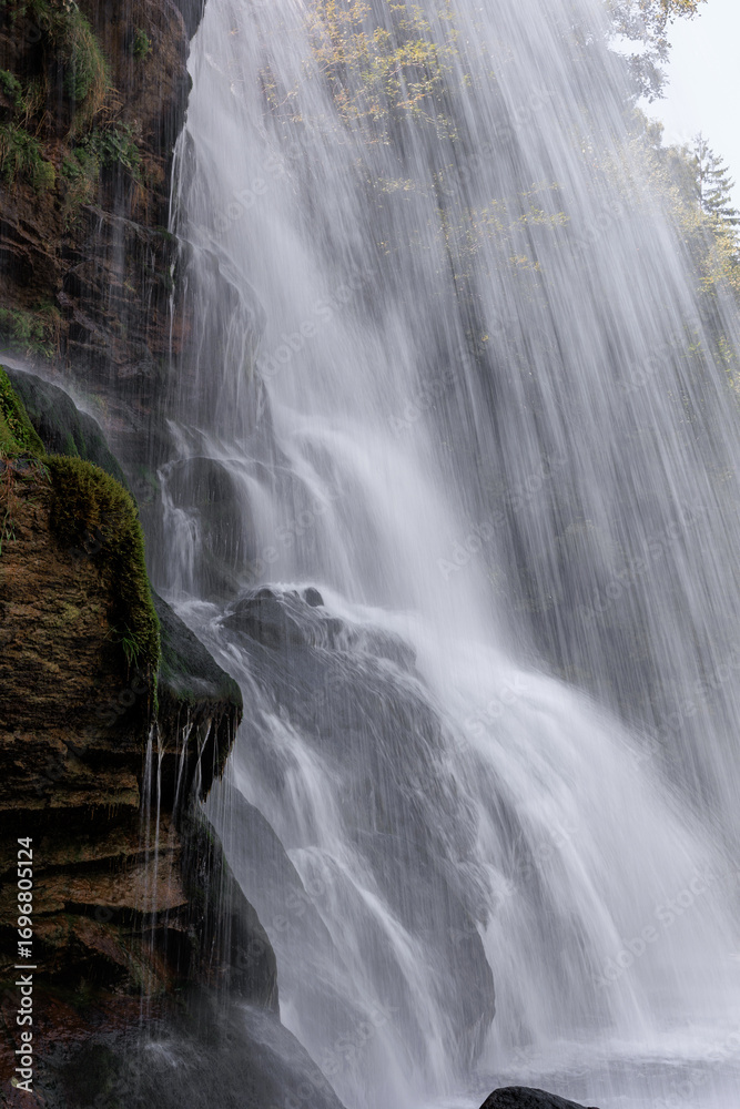 Fototapeta premium Scenic Waterfall in the Swiss Alps, Switzerland. Beautiful waterfall in the Swiss Alps, Switzerland, surrounded by mountains and nature. Scenic alpine landscape with flowing water, rocks, and forest,