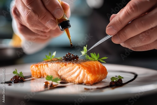 Chef garnishing salmon fillet with caviar and herbs.