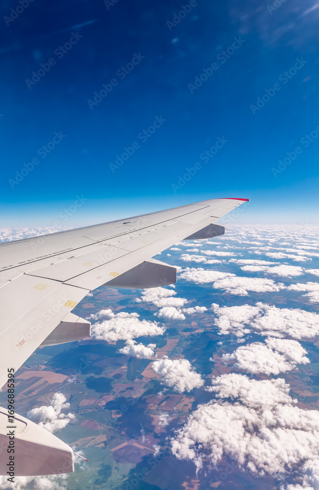 Fototapeta premium View from the airplane window at a beautiful cloudy sky and the airplane wing