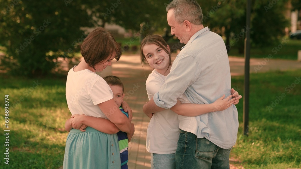 Fototapeta premium Children running to dad mom hugging together in park. Family walk outdoors hugging mother father and girl. Family children parents walking in park. Family support care weekend in nature park in summer