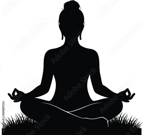 Silhouette of a woman meditating in a seated yoga pose on grass.