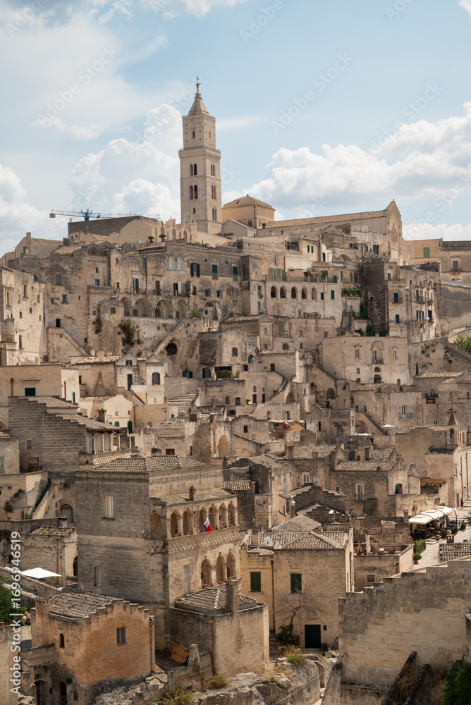 Fototapeta premium Historic stone city of Matera, Italy. Ancient cave dwellings and medieval architecture built into the rock, UNESCO World Heritage site. Panoramic view with dramatic sky.