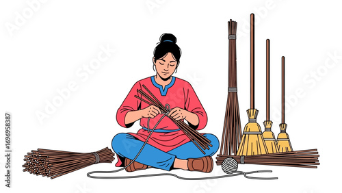 Crafting Tradition: An individual sits cross-legged, meticulously weaving the bristles of a traditional broom. Captured from a high angle, highlighting skill and culture.