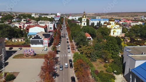 Drone moving forward along the central boulevard of Comrat with trees and historic buildings.