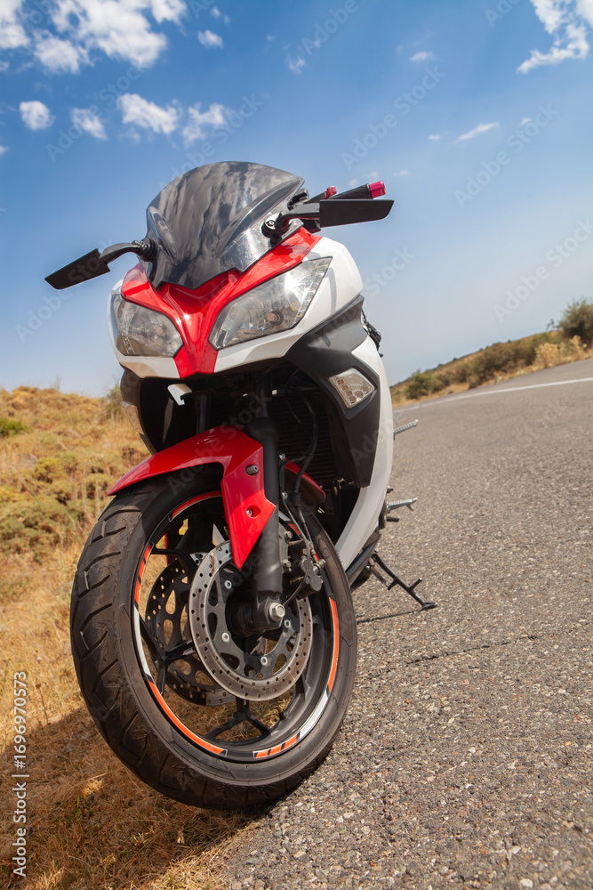 Obraz premium Rear view of a black and red motorcycle on the road.