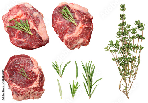 Set of three raw steaks garnished with rosemary sprigs and a bunch of fresh thyme
