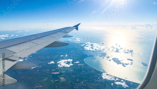 High-angle view from an airplane window reveals a stunning landscape of coastal landmasses and a glistening sea, bathed in bright sunlight.