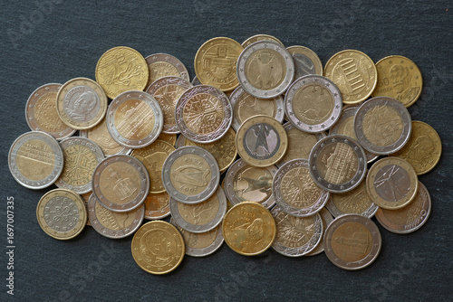 Euro coins lie in bulk on a black background, top view