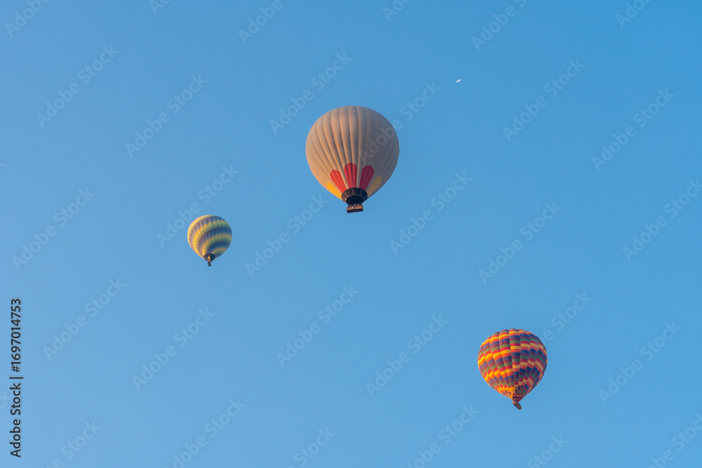 Obraz premium Three hot air balloons against a blue sky. Beautiful view of colourful hot air balloons from below. Cappadocia