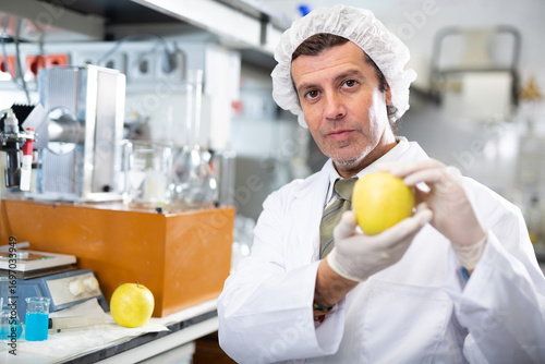 Geneticist working in laboratory, injecting additives into apple during experiments with genetically modified fruits