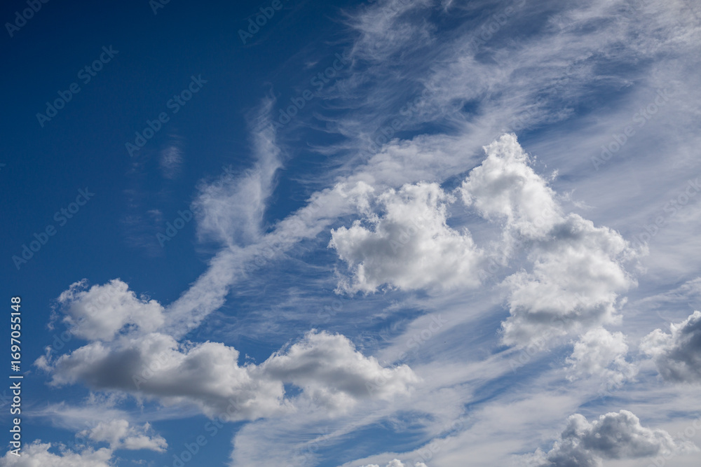 Fototapeta premium White fluffy clouds against a blue sky. Natural cloud formations in a bright daytime view.